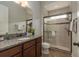 Bathroom with granite counter, wooden cabinets, a glass-door shower, and a toilet at 4583 Barletta Ct, Wesley Chapel, FL 33543