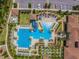 Aerial view of a bright blue community pool featuring slides, a swimming area, lounge chairs, and lush landscaping at 4583 Barletta Ct, Wesley Chapel, FL 33543