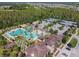Aerial view of a community pool, playground, tennis courts, and clubhouse surrounded by lush greenery at 4583 Barletta Ct, Wesley Chapel, FL 33543
