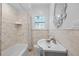 Bright bathroom featuring marble tile, a stylish sink, and a shower-tub combination at 475 28Th N Ave, St Petersburg, FL 33704