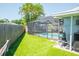 View of the artificial turf backyard with screen porch enclosing a pool with an open view on a sunny day at 489 Fox Run Trl, Apollo Beach, FL 33572