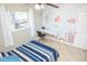 Bright bedroom features a bed with blue striped bedding, artwork, and a ceiling fan at 489 Fox Run Trl, Apollo Beach, FL 33572