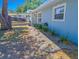 Charming exterior of the blue home, featuring a rock garden with lawn lights and a covered parking area with a boat at 489 Fox Run Trl, Apollo Beach, FL 33572