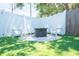Backyard fire pit surrounded by Adirondack chairs and a white privacy fence on an artificial turf yard at 489 Fox Run Trl, Apollo Beach, FL 33572