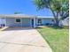 This home features a front yard, long concrete driveway, a carport, and a light-blue painted exterior at 489 Fox Run Trl, Apollo Beach, FL 33572