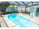 A large screened pool is surrounded by a patio table, and turf, with a fence at 489 Fox Run Trl, Apollo Beach, FL 33572