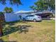 White car sits on the grass near a white privacy fence with a boat beyond, under a sunny blue sky at 489 Fox Run Trl, Apollo Beach, FL 33572