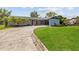 Charming single-story home with an expansive driveway, lush lawn, mature palm trees, and covered carport at 5109 Vinson Dr, Tampa, FL 33610