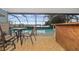 Screened-in pool area with a table, chairs, and a rustic wood bar, offering a scenic lake view at 5109 Vinson Dr, Tampa, FL 33610