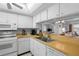 Clean kitchen with white cabinets, appliances, and a convenient breakfast bar to the living area at 5157 Silent Loop # 208, New Port Richey, FL 34652
