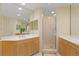 Bathroom with double sinks, wood cabinets, glass shower, and tile floor at 521 Mandalay Ave # 307, Clearwater Beach, FL 33767