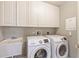 Laundry room featuring modern white appliances, overhead cabinets, and a utility sink at 521 Mandalay Ave # 307, Clearwater Beach, FL 33767