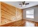 Bedroom features wood wall paneling, wood floors and a ceiling fan at 5435 Birchwood Rd, Spring Hill, FL 34608