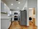 Open kitchen design featuring stainless appliances, white cabinetry, and wood-look laminate flooring at 5435 Birchwood Rd, Spring Hill, FL 34608