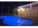 Night view of a private in-ground pool with bright blue lighting inside a screened enclosure at 5435 Birchwood Rd, Spring Hill, FL 34608