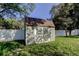 Backyard storage shed with white trim and a brown shingled roof, secured behind a white privacy fence at 5435 Birchwood Rd, Spring Hill, FL 34608