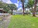 Backyard featuring a charming home, mature trees providing shade, and a well-maintained lawn at 5720 Half Moon Lake Rd, Tampa, FL 33625