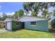Green home exterior featuring a connected garage, well-maintained lawn, and mature trees providing ample shade at 5720 Half Moon Lake Rd, Tampa, FL 33625
