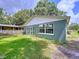 Charming home exterior with large windows, a well-maintained lawn, and a peaceful backyard setting at 5720 Half Moon Lake Rd, Tampa, FL 33625
