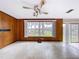 Spacious living room with a ceiling fan, large window with lake view, and classic wood paneling at 5720 Half Moon Lake Rd, Tampa, FL 33625