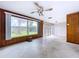 Spacious living room featuring a ceiling fan, large windows, and wood paneled walls at 5720 Half Moon Lake Rd, Tampa, FL 33625