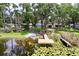 Lakeside home featuring a private dock, boat, and jet ski, nestled among lush trees and vibrant lily pads at 5720 Half Moon Lake Rd, Tampa, FL 33625