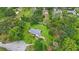 Aerial view of a single-story home surrounded by lush greenery, mature trees, and a well-maintained lawn at 5933 Carina Trce, Wesley Chapel, FL 33545