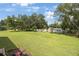 Expansive backyard with a storage shed, lush green grass, and mature trees at 5933 Carina Trce, Wesley Chapel, FL 33545