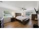 Comfortable bedroom with hardwood floors, ceiling fan, and plenty of natural light from two large windows at 5933 Carina Trce, Wesley Chapel, FL 33545
