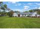 Beautifully maintained home features a lush green lawn, mature landscaping, and a welcoming red front door at 5933 Carina Trce, Wesley Chapel, FL 33545