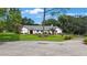 Charming single-story home featuring a lush front lawn, mature trees and bushes, and a welcoming red front door at 5933 Carina Trce, Wesley Chapel, FL 33545
