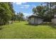 Backyard view featuring a wooden shed, surrounded by lush grass and mature trees, offering ample storage space at 5933 Carina Trce, Wesley Chapel, FL 33545