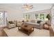 Bright living room featuring modern furnishings, wood-look flooring, a ceiling fan, and a view of the front yard at 6489 30Th N St, St Petersburg, FL 33702