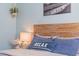 Close up of a bedroom decor with a wooden headboard, lamp, 'Relax' pillow, and beach-themed artwork on blue walls at 6611 Surfside Blvd, Apollo Beach, FL 33572