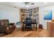 Cozy home office featuring built-in shelving, a ceiling fan, and warm wood flooring at 6611 Surfside Blvd, Apollo Beach, FL 33572