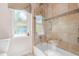 Charming bathroom featuring a glass enclosed tub and shower combo, decorative tile and window at 6627 Date Palm S Ave, St Petersburg, FL 33707