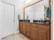 Bathroom with a double vanity, granite countertop, wood cabinets, and a large mirror at 6627 Date Palm S Ave, St Petersburg, FL 33707