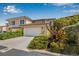 Two-story home with a two-car garage surrounded by lush landscaping including tropical plants and colorful flowers at 6627 Date Palm S Ave, St Petersburg, FL 33707