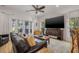Open living room with hardwood floors, ceiling fan, large windows, and comfortable leather seating at 6627 Date Palm S Ave, St Petersburg, FL 33707