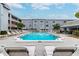 Community pool with lounge chairs surrounded by lush landscaping and multi-story building at 701 Poinsettia Rd # 340, Belleair, FL 33756