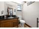 Half-bathroom featuring a black granite countertop, wooden vanity, and toilet, with a mirror reflecting the adjacent interior at 717 E 137Th Ave, Tampa, FL 33613