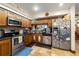 Well-lit kitchen featuring stainless steel appliances, wooden cabinets, backsplash, and tile floor, and a window above the sink at 717 E 137Th Ave, Tampa, FL 33613