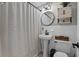 Bathroom with white tiling, pedestal sink, rounded mirror and a shower with curtain at 7304 Lakeside Blvd, Tampa, FL 33614
