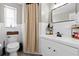 Bright bathroom featuring white tile, a shower curtain, toilet, and vanity with storage space at 7304 Lakeside Blvd, Tampa, FL 33614