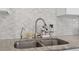 Close up of the stainless steel dual kitchen sink with stainless faucet with a tiled back splash at 7304 Lakeside Blvd, Tampa, FL 33614