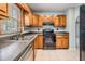 Efficient kitchen with wood cabinets, neutral countertops, and a black range at 7347 Pulsar St, New Port Richey, FL 34652