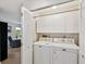 Functional laundry area featuring a washer, dryer, cabinet storage, and folding doors for added convenience at 7360 Ulmerton Rd # 18A, Largo, FL 33771