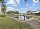 Community pond with dock featuring manicured landscaping, palm trees, and beautiful views at 7360 Ulmerton Rd # 18A, Largo, FL 33771