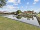 Community pond featuring manicured landscaping, palm trees, tranquil water, and residential homes at 7360 Ulmerton Rd # 18A, Largo, FL 33771