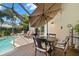 Inviting outdoor patio with screened pool, dining table, chairs, and lush greenery at 8708 Laurel N Dr, Pinellas Park, FL 33782